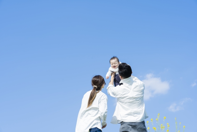 赤ちゃんを高く抱き上げる新婚カップル
