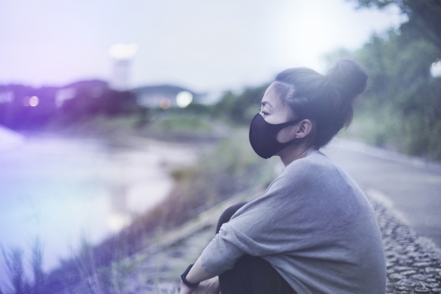 ひとりぼっちで川岸にうずくまる女性