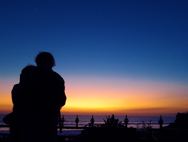 夕暮れの海岸に寄り添うカップル
